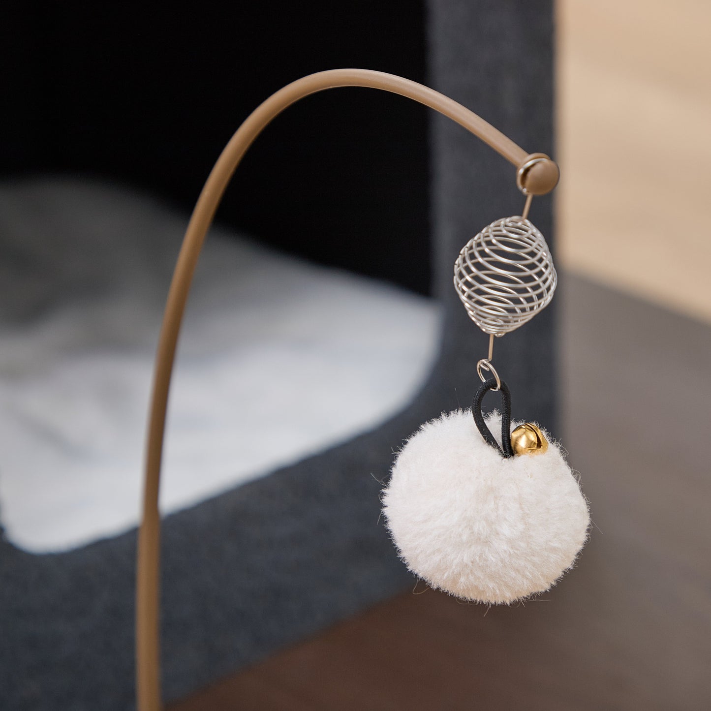 Catry Trinity CT240359 cat tree with a swivel dangling white pom-pom cat toy ball with a small bell on a blurred background.